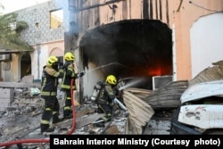 Bahraini firefighters try to extinguish the flames caused by an Iranian drone attack
