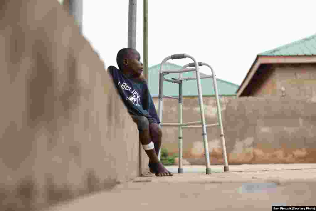 A former child slave sits and watches other kids play.