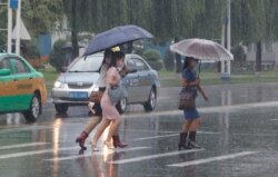 Warga Pyongyang berjalan dengan membawa payung, dibawah guyuran hujan lebat, 5 Agustus 2020.