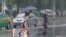 Women walk with umbrellas during torrential rains, August 5, 2020, in Pyongyang.