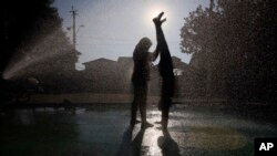 FILE - Children cooling off at a water fountain during a heat wave in Santiago, Chile.