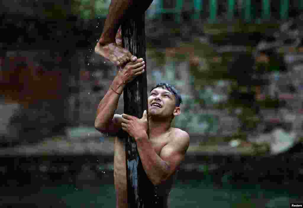 A devotee helps his friend to climb the wooden pole during the Deopokhari festival in Khokana, Nepal, Aug. 9, 2017.