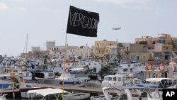 Sebuah bendera hitam bertuliskan "Vergogna" (malu) dikibarkan di pelabuhan pulau Lampedusa, Italia (4/10). Italia berkabung pasca tenggelamnya kapal yang mengangkut pencari suaka dari Eritrea dan Somalia di dekalt pulau Lampedusa, Kamis (3/10). Sekitar 300 orang dinyatakan tewas dalam insiden tersebut.