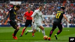 Cristiano Ronaldo du Real Madrid, au centre, perce avec le ballon entre Gerard Moreno de l'Espanyol, à gauche, et le co-équipier de ce dernier, Hernan Perez, lors d'un match de la La Liga espagnole au stade Santiago Bernabeu à Madrid, 18 février 2017. 