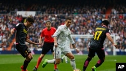 Cristiano Ronaldo du Real Madrid, au centre, perce avec le ballon entre Gerard Moreno de l'Espanyol, à gauche, et le co-équipier de ce dernier, Hernan Perez, lors d'un match de la La Liga espagnole au stade Santiago Bernabeu à Madrid, 18 février 2017. 