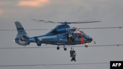 A police helicopter lifts an evacuee with a rescue police officer from floodwaters in Joso city in Ibaraki prefecture, north of Tokyo, Sept. 10, 2015. 