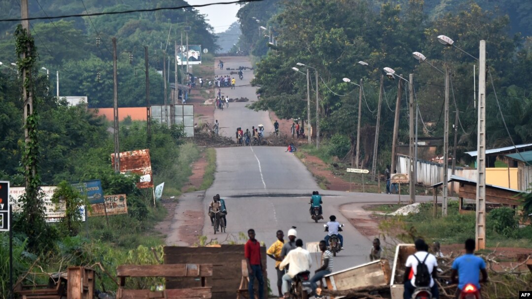 People stand near barricades as they protest against a third term of incumbent Ivory Coast President at the entrance of Daoukro, Nov. 2, 2020.