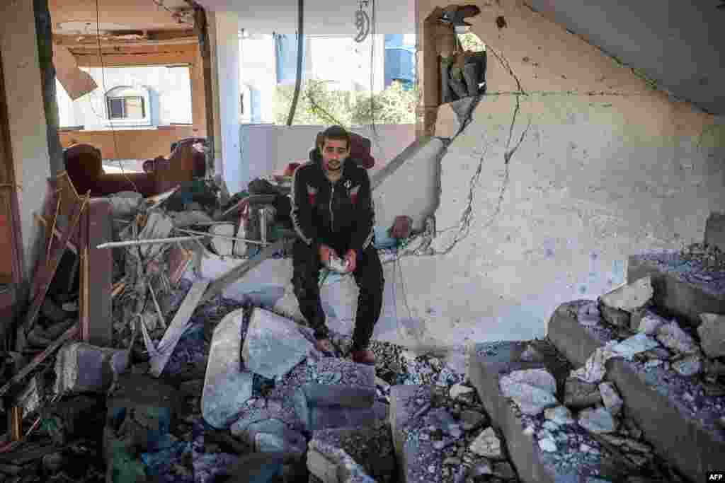 A man reacts as he sits in a heavily damaged building following an Israeli strike in Deir Al-Balah in the central Gaza Strip, amid the ongoing war between Israel and the Palestinian Hamas militant group.