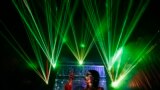 A visitor takes pictures with her mobile phone in front of laser beams and a projected image of the Arc de Triomphe, at the 2013 Optic Valley of China International Optoelectronic Exposition and Forum (OVC EXPO) in Wuhan, Hubei province, China. 
