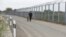 FILE - A police officer with a dog patrols the border fence on the Hungarian-Serbian border near Roszke, 180 kms southeast of Budapest, Hungary, April 28, 2017. Hungary has asked the EU to pay half of the cost of the fence built to keep illegal immigrants