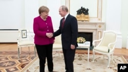 Russian President Vladimir Putin, right, and German Chancellor Angela Merkel Greer each other prior to the talks in the Kremlin in Moscow, Russia, Jan. 11, 2020.