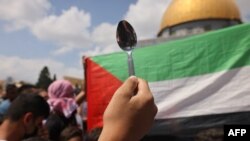 A person holds up a spoon, reportedly the digging tool used by six Palestinian prisoners who escaped from Israel's Gilboa prison, during a gathering in front of the Dome of the Rock mosque in Jerusalem on Sept. 10, 2021.