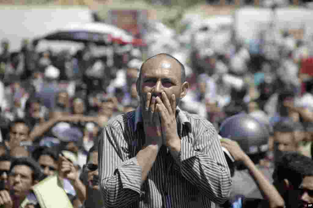 A man reacts as he watches the trial of former President Hosni Mubarak on a giant screen outside the police academy in Cairo. (AP Image)