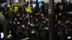 As members of the ruling People Power Party try to block them, police try to enter the gate of the presidential residence in Seoul, South Korea, early on Jan. 15, 2025.