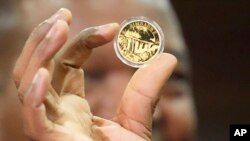 FILE - John Mangudya, Reserve Bank of Zimbabwe governor, holds a sample of a gold coin at the launch in Harare, July, 25, 2022.