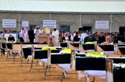 FILE - Mourners prepare to bury the remains of Yazidi victims in a cemetery in Sinjar, Iraq, Feb. 6, 2021. 104 Yazidi killed by the Islamic State group six years ago were given a proper burial in a cemetery in Sinjar's Kocho village.