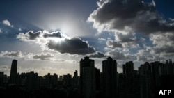 Buildings are silhouetted as clouds drift past the sun in Shanghai on Sept. 17, 2024. 