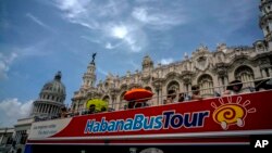 FILE - In this June 17, 2017, photo, tourists ride a tour bus in front of the Capitolio in Havana, Cuba.