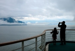 FILE - In this July 28, 2014, file photo, a cruise ship passenger takes photos of Alaska's Inside Passage. The Canadian government has extended a ban on cruise ships through February 2022.