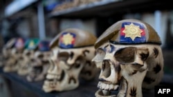 FILE - A display of carvings that depict human skulls in beret's bearing military insignia of British Army companies that are popular with troops that come to Laikipia to train under the British Army Training Unit in Kenya in Nanyuki town, Laikipia county on October 17, 2023. 