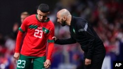 Morocco's coach Walid Regragui, right, talks to Bilal El Khannouss during the International friendly soccer match between Morocco and Peru at the Civitas Metropolitano stadium in Madrid, Spain, Tuesday, March 28, 2023. 