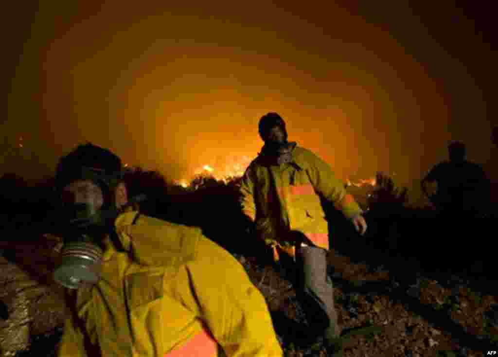 Firefighters walk near an extensive fire in Tirat Hacarmel, northern Israel, Thursday, Dec. 2, 2010. A massive forest fire that scorched part of northern Israel killed scores of people Thursday, officials said. Fire officials said the blaze, which torched