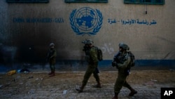 چند سرباز اسرائیلی در مقابل مقر آژانس امدادرسانی و کاریابی برای آوارگان فلسطینی، اونروا، در غزه.