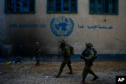 FILE - Israeli soldiers take position as they enter the UNRWA headquartes where the military discovered tunnels beneath of the U.N. agency, February 8, 2024