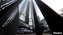 FILE - Police vehicles are parked in front of Deutsche Bank headquarters as roughly 170 criminal police officers, prosecutors and tax inspectors searched Deutsche Bank offices in and around Frankfurt, Germany, Nov. 29, 2018, on money laundering allegations.