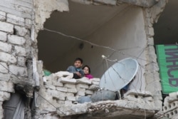 FILE - Children peer from a badly damaged home in Aleppo, Syria, Feb. 11, 2016.
