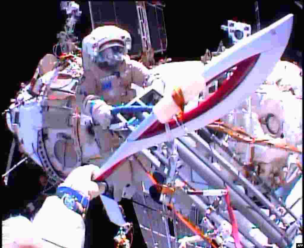 In this image obtained from NASA TV, Cosmonauts Oleg Kotov and Sergei Ryazansky (rear) perform a handoff of the Sochi 2014 Winter Olympic Games Torch during a spacewalk outside the International Space Station, Nov. 9, 2013.