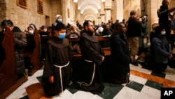 Members of the clergy attend a Christmas midnight Mass at Saint Catherine's Church, in the Church of the Nativity, in Bethlehem, in the Israeli-occupied West Bank, Dec. 25, 2021.