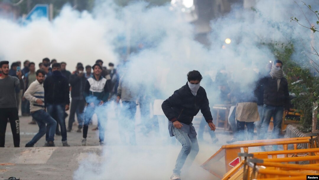 Protesters run for cover amid tear gas fired by police during a protest against the Citizenship Amendment Bill, New Delhi, Dec. 13, 2019. 