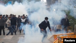 Protesters run for cover amid tear gas fired by police during a protest against the Citizenship Amendment Bill, New Delhi, Dec. 13, 2019. 