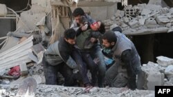 Syrians rescue a child following a reported government airstrike in the rebel-held town of Hamouria, in the besieged Eastern Ghouta region on the outskirts of the capital Damascus, Feb. 21, 2018. 