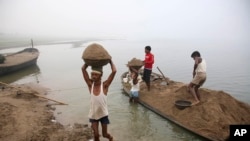 FILE - Laborers transport sand from boats to the shore after excavations from the bed of the River Yamuna in Allahabad, India, Nov. 19, 2011. Greater construction in India has led to a high demand for river sand, which leads to indiscriminate mining.