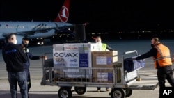 FILE - Airport personal unload the first batch of the AstraZeneca vaccines sent from the Covax facility, at Adem Jashari airport Pristina, Kosovo, March 28, 2021.