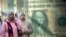 FILE - Egyptians walk past a poster depicting a U.S. dollar outside an exchange office in Cairo, Egypt, February. 9, 2023.
