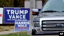 Politically opposed neighbors post campaign signs in their yards, Oct. 31, 2024, in Janesville, Wisconsin.