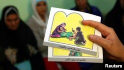 FILE - A counselor holds up cards used to educate women about female genital mutilation (FGM).