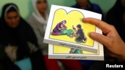 FILE - A counselor holds up cards used to educate women about female genital mutilation (FGM).