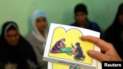 FILE - A counselor holds up cards used to educate women about female genital mutilation (FGM).