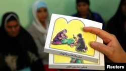 FILE - A counselor holds up cards used to educate women about female genital mutilation (FGM).