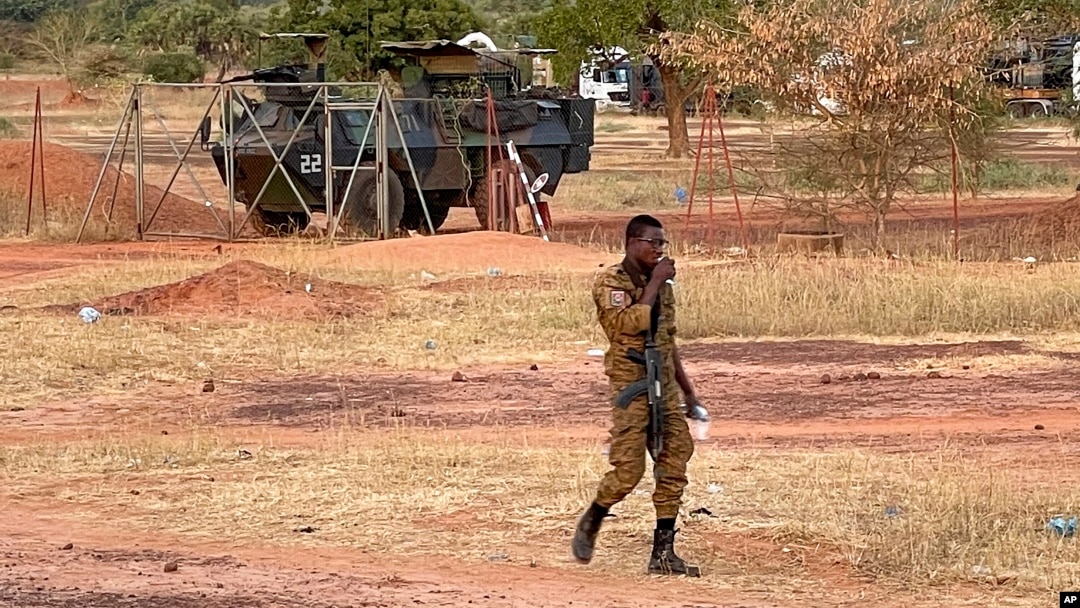 A Burkinabe soldier walks past a French Armoured Personnel Carrier part of a French military convoy heading to Niger, stopped by protesters in Kaya, Burkina Faso, Nov. 20, 2021.