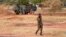 A Burkinabe soldier walks past a French Armoured Personnel Carrier part of a French military convoy heading to Niger, stopped by protesters in Kaya, Burkina Faso, Nov. 20, 2021.