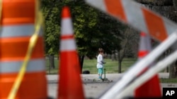 A child rides a scooter past barricades at an entrance to Tower Grove Park in St. Louis, Missouri, March 31, 2020.