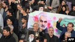 Warga Iran membawa spanduk dengan gambar Mayor Jenderal Qasem Soleimani dari Garda Revolusioner Iran yang terbunuh dalam serangan drone oleh AS, 3 Januari 2020. (Foto: AFP)