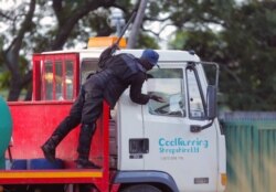 A riot police officer demands a clearance letter to be on the road from a water delivery truck driver, during lockdown due to coronavirus in Harare, Zimbabwe, April 8, 2020.