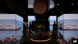 People walk through the TCL booth during the CES tech show Wednesday, Jan. 8, 2025, in Las Vegas. (AP Photo/John Locher)