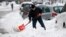 Un hombre palea para tratar de desatascar su vehículo que quedó atrapado por la nieve en Nueva York. 